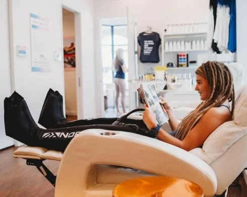 Woman in chair receiving Normatec Compression Leg Massage.